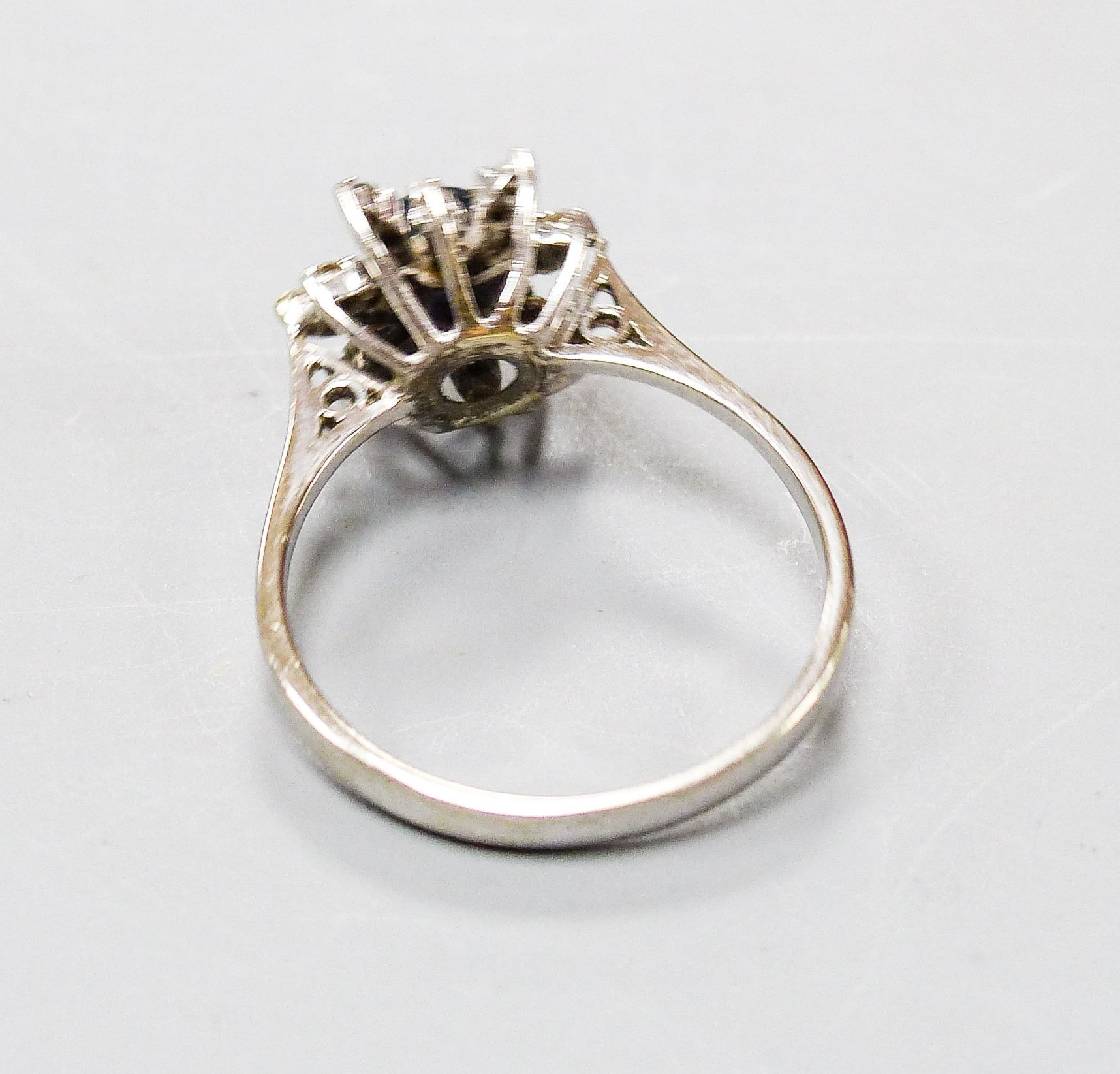 An 18ct white metal, sapphire and diamond set flower head cluster ring, size O, gross 3 grams.